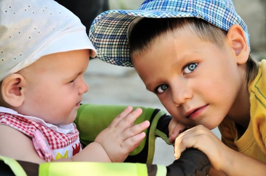 young boy holding  carriage  of  his baby sister