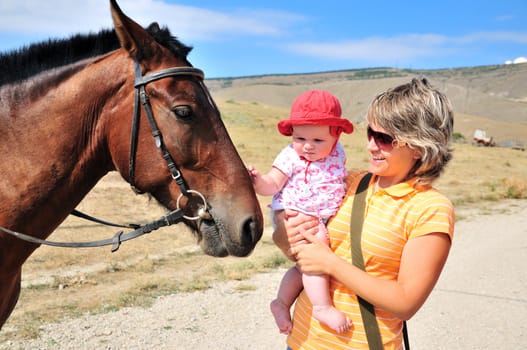 mother habituating her little daughter with horse 