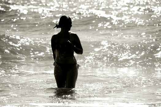 silhouette of a wet young woman in a waving sea