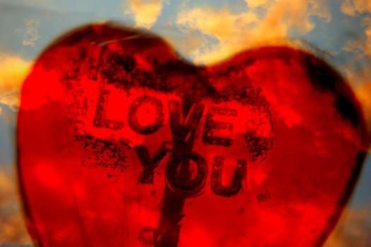 love message on red heart shaped lollipop against vanilla sky background