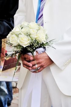 groom wearing white suit brought a flowers for bride