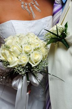 groom's boutonniere and bride's flowers on wedding day