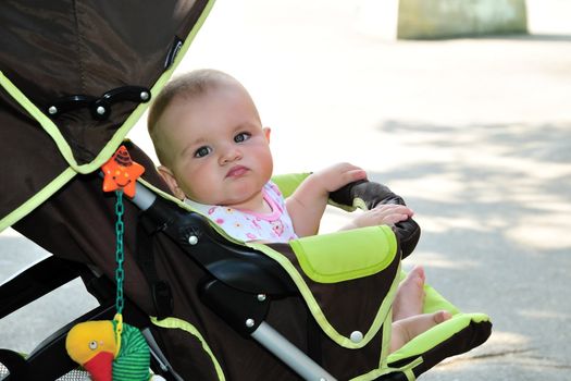 funny baby is sitting in her stroller