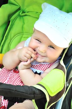 funny baby is sitting in her stroller