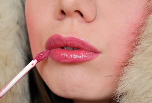 close-up of girl's lips who applying  lip-gloss