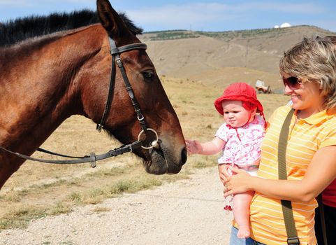 mother habituating her little daughter with horse
