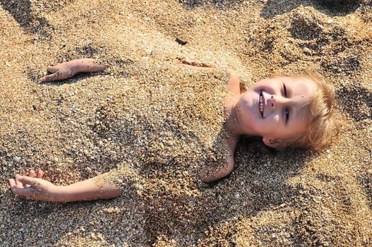 little boy is dug in sand  on the beach