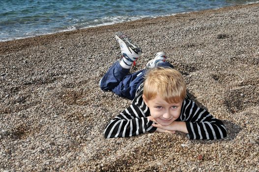 boy is laying at the beach in autumn time