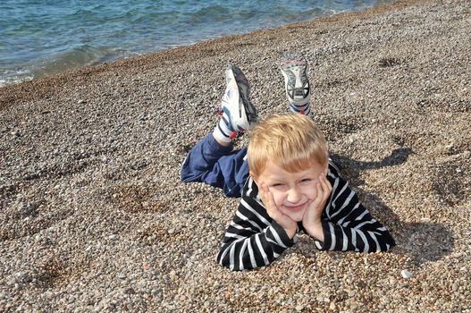 boy is laying at the beach in autumn time