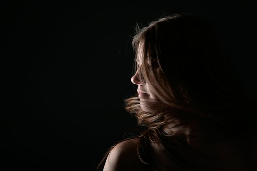 Young woman portrait on the wind with black background