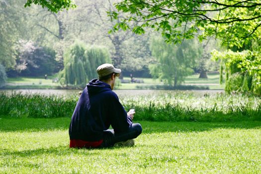 young man using a cellphone while resting in park