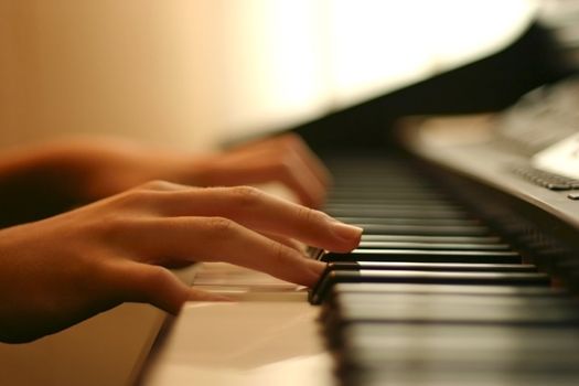 close-up of a piano player hands gently touching the keys