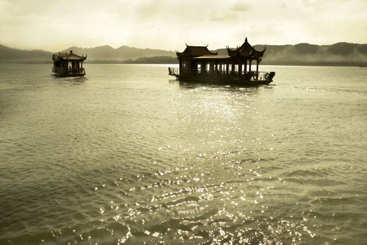 floating houses in West Lake with foggy mountain scenery in background, Hangzhou, China