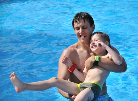 father teaching his little son to swim, they are smiling, they are happy