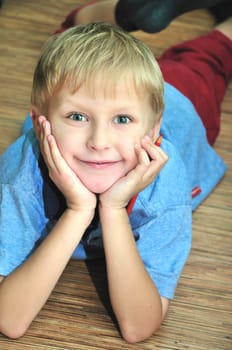 boy laying on the wooden floor, he taking a pencil