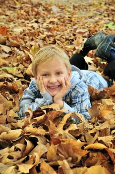 Young boy laying in the autumn leaves