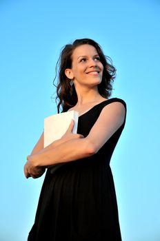 beautiful girl taking book ( it's possible to write anything  on it) over blue background 