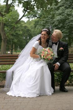 just married pair rests on bench in park, Riga, Latvia