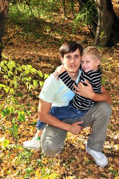 boy embracing his father in the forest in fall time