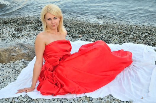 lady in red is sitting on the beach, alone