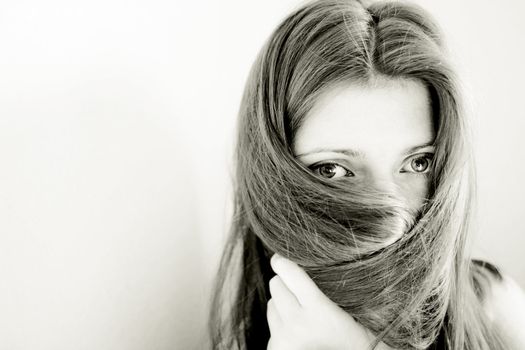 young woman hiding her face with long straight brown hair