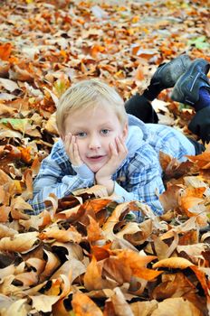 Young boy laying in the autumn leaves