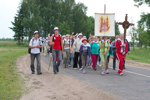 Youth piligrims from Roman Catholic church on their piligrimage, singing and chanting, two girls holding Cross and banner of local village Miory, Belarus