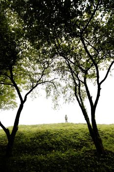 young boy sings on a green hill, wide angle perspective