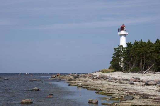 Tall white lighthouse on the rocky coast