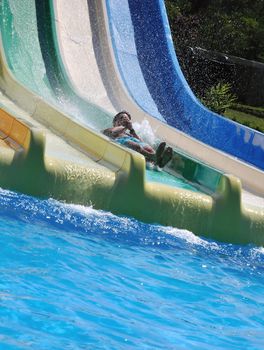 outdoor water park , man is driving down rapid descent