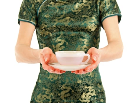 Woman in green Chinese dress offering a cup of tea. Focus on the cup.