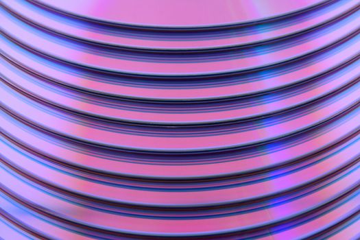 Abstract purple technology background. Closeup of stacked CDs.