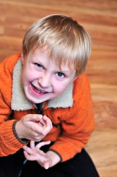 Little blonde boy making grimace and sitting on the deck 