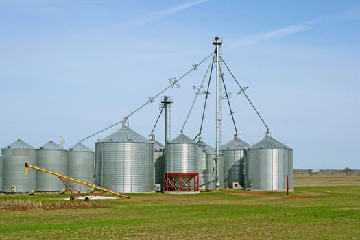 Grain silos on a farm in green spring field.