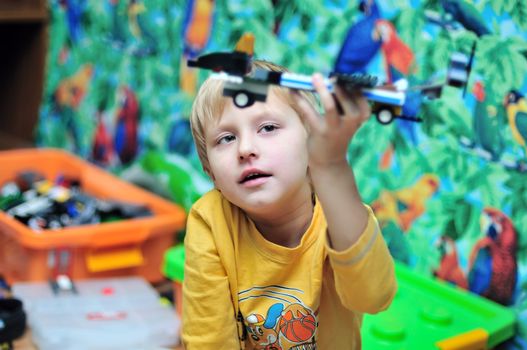 little boy made a plane from constructor and playing in his own room