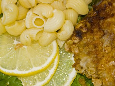 The image of macaroni, of a fish and slices of a lemon close up