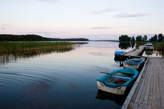 Calm summer evening at forest lake with moored boats