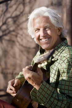 Handsome man playing an old acoustic guitar