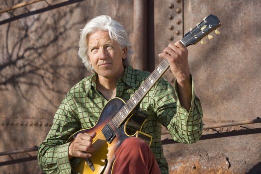 Handsome man playing an old acoustic guitar