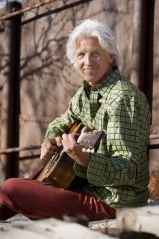 Handsome man playing an old acoustic guitar