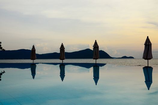 The umbrellas reflecting in calm water of swimming pool