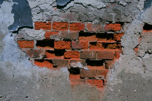 A ruined wall showing his heart of stones behind the stucco surface.