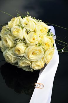 yellow  roses and wedding bands on the dark surface