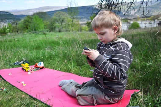 little boy outdoors does not want to play toys, he wants mobile phone