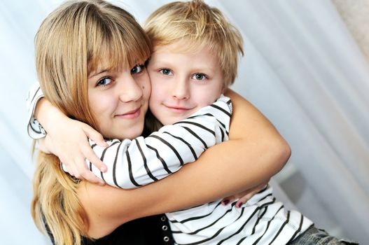 Brother and sister at home smiling and embracing
