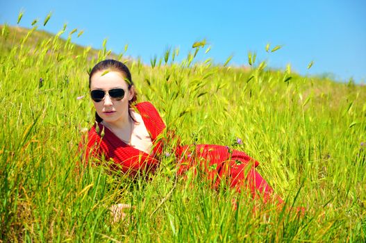 pretty girl laying in green grass in summer time