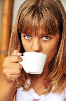 tanned teen girl is drinking something from cup