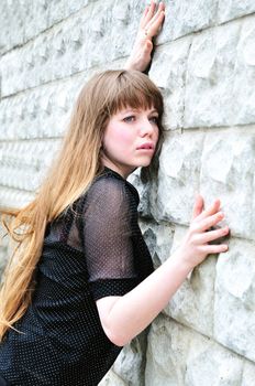 Blue-eyed long-haired girl leans on elbow wall 