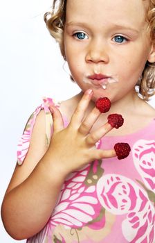 funny young girl enjoying a fresh raspberries stacking on her fingers

