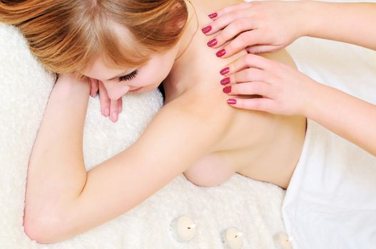 pretty young woman relaxing under hands of  massage therapist
